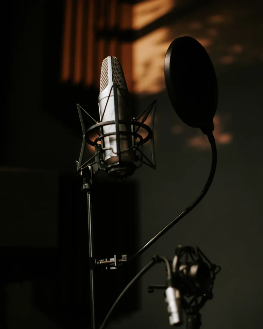 Micrófono de estudio con filtro antipop en una sala de grabación con poca luz