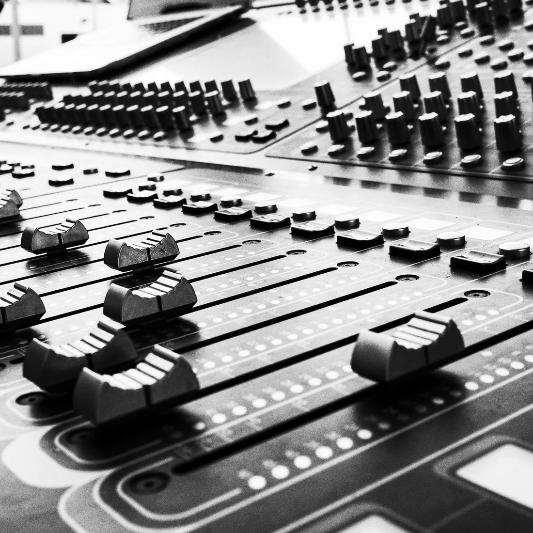 Mesa de mezclas de estudio con faders y potenciómetros vista de cerca